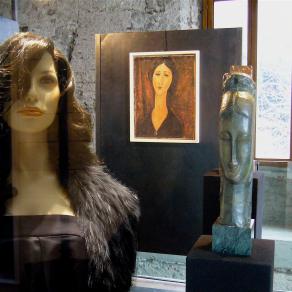 Manichino che si fa fotografare davanti a delle opere di una mostra di Modigliani