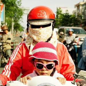 Woman with a colored "Cover-up Style" and her daughter driving on the streets of H.C.M.C. Woman with a colored