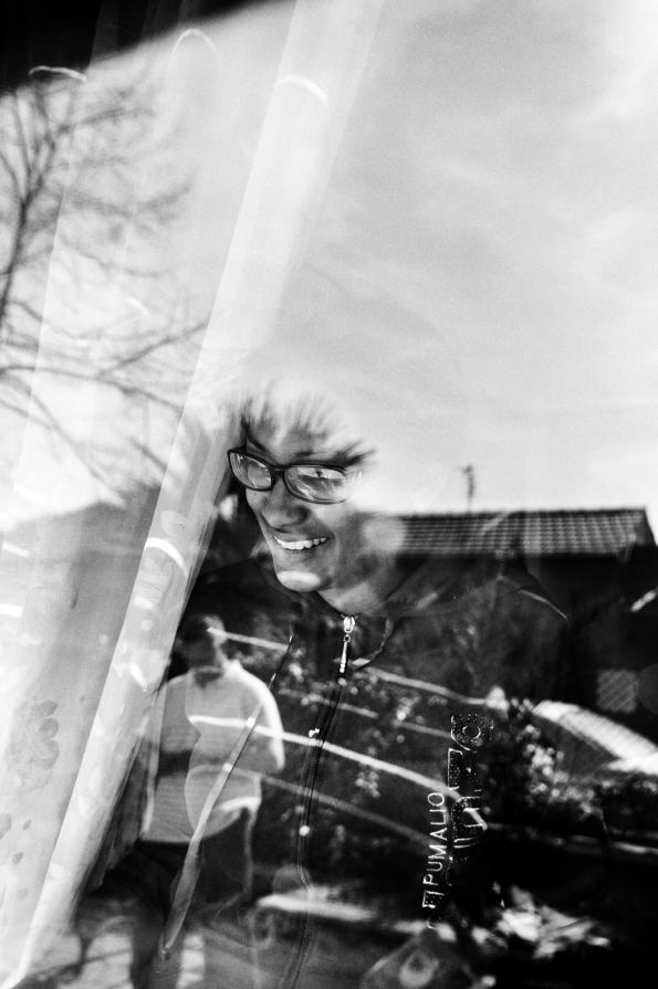 Nelly controlla da dietro la finestra della sua nuova situazione abitativa, una piccola chiesetta alla periferia di Roma,il gioco dei suoi 2 figli